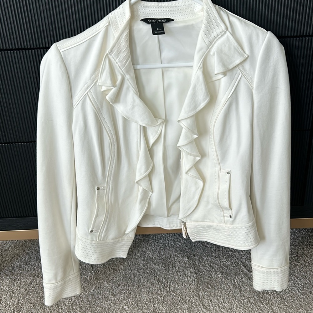 Off white short jacket with detailing and ruffled edges.